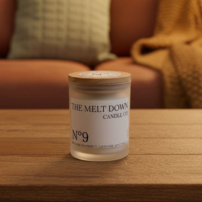 Candle jar labeled 'The Melt Down Candle Co.' on a wooden surface with a window in the background.