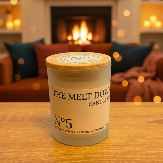 Candle labeled 'The Melt Down Candles' on a wooden surface with a blurred background