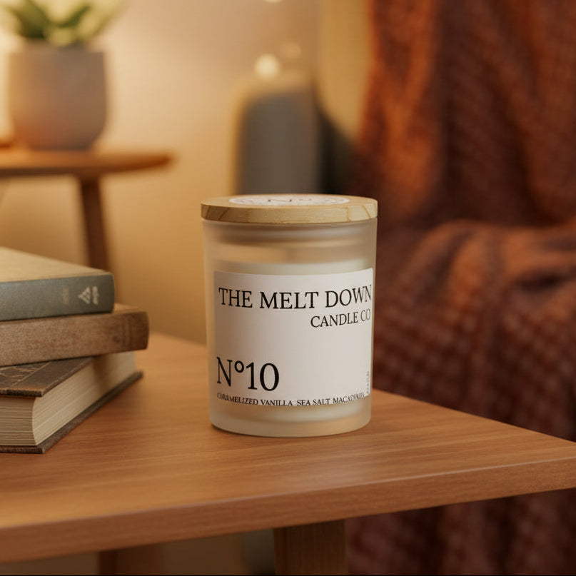 Candle labeled 'The Melt Down Candle Co.' on a wooden surface with books and a blurred background